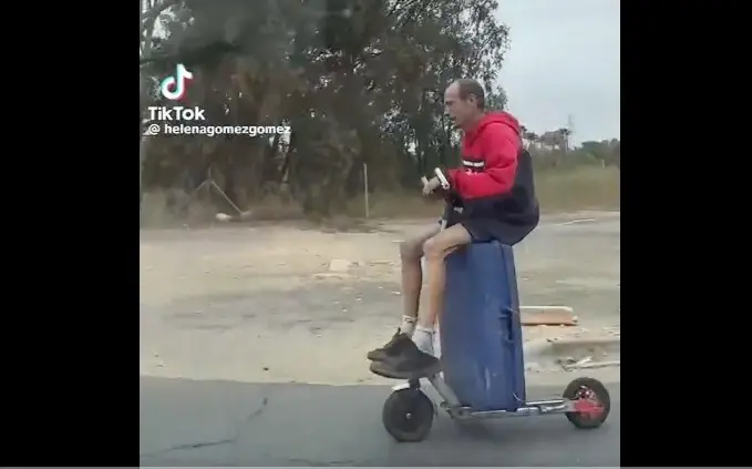 Hombre viaja montado en una maleta