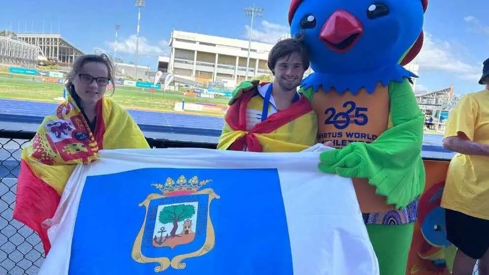 Blanca y Nicol&aacute;s con la bandera de Huelva en el mundial de atletismo. Fuente: Facebook Blanca Betanzos