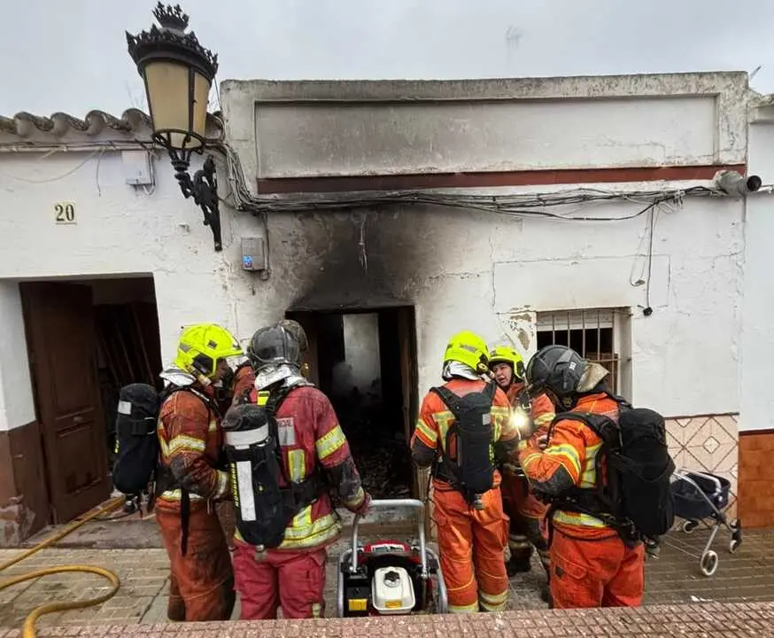 Bomberos ante la vivienda incendiada en Villalba del Alcor