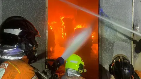 Bomberos del Consorcio sofocando las llamas del incendio en una nave industrial en La Palma del Condado