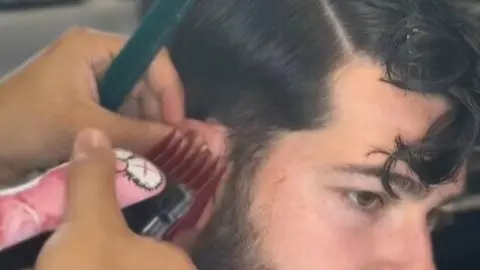 El artista cort&aacute;ndose el pelo antes de realizar la obra de arte. Fuente: Tiktok de @fabre_artista