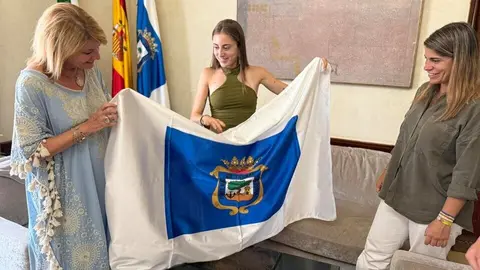 Mar&iacute;a Forero posa junto a Pilar Miranda con la bandera de Huelva. Fuente: Ayto. Huelva