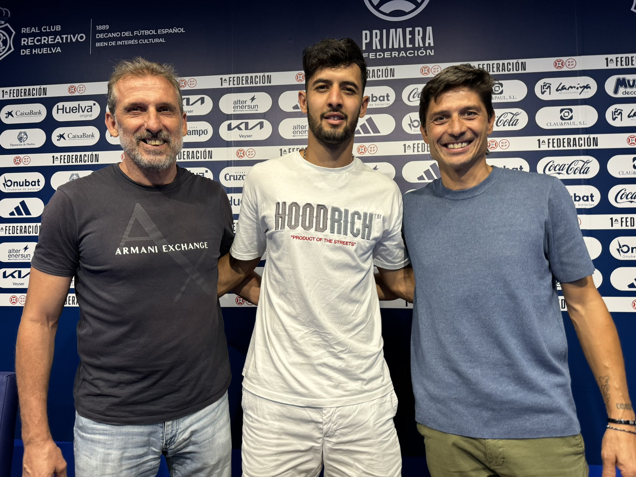 El argentino posa en la sala de prensa junto al director deportivo y el Presidente del Decano. Fuente: Twitter Recreativo de Huelva